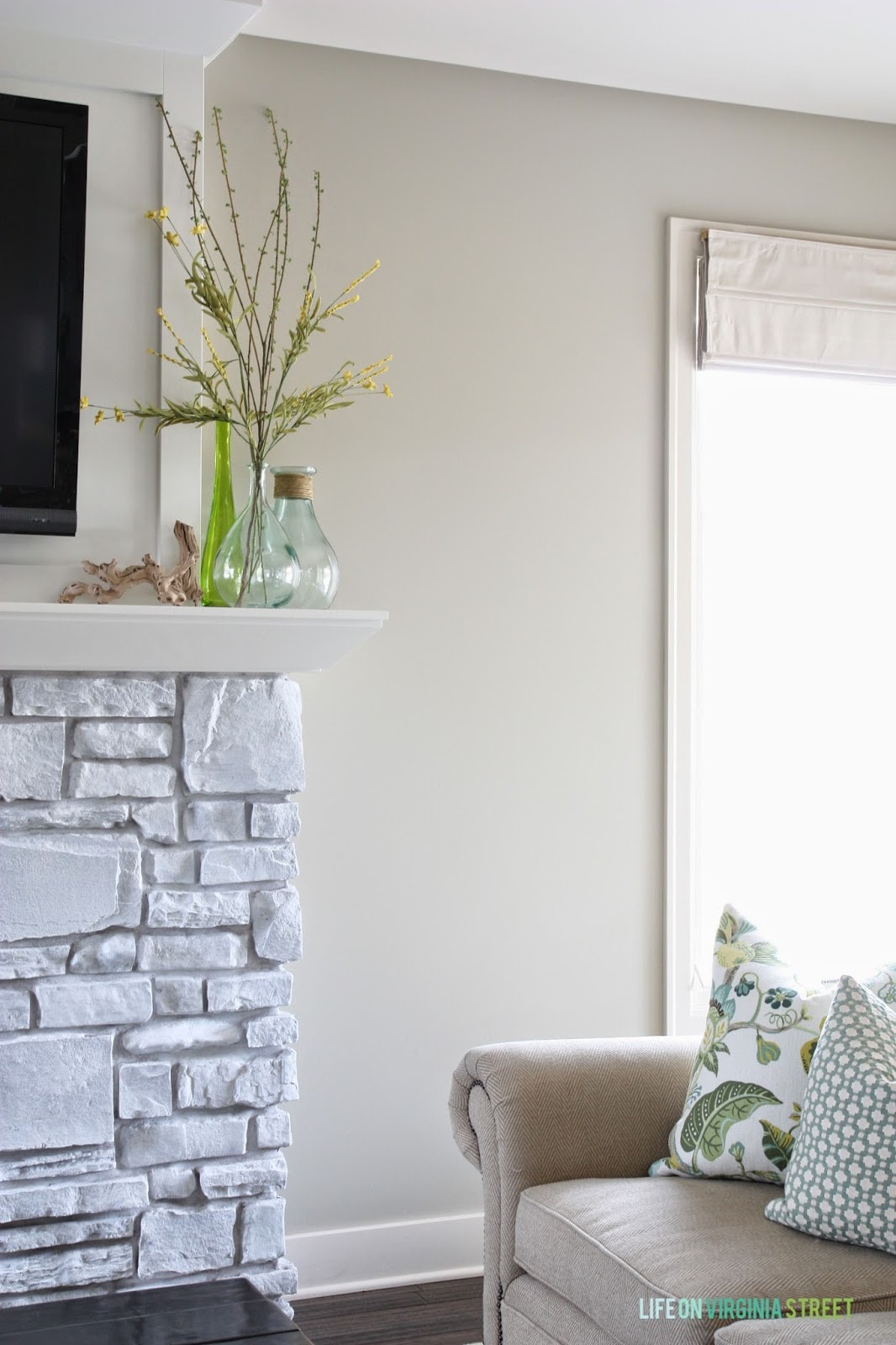 Side view of the fireplace with a neutral couch and throw pillows.