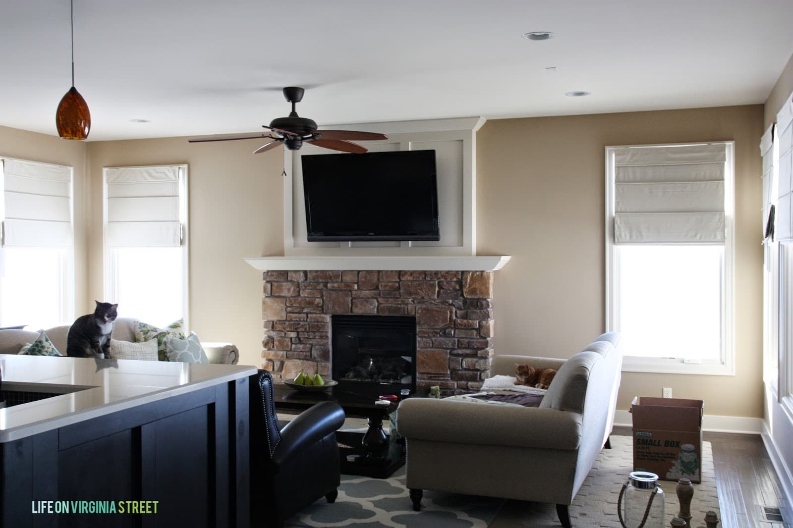 A brown and orange stone fireplace before it was whitewashed with couches in front of it.