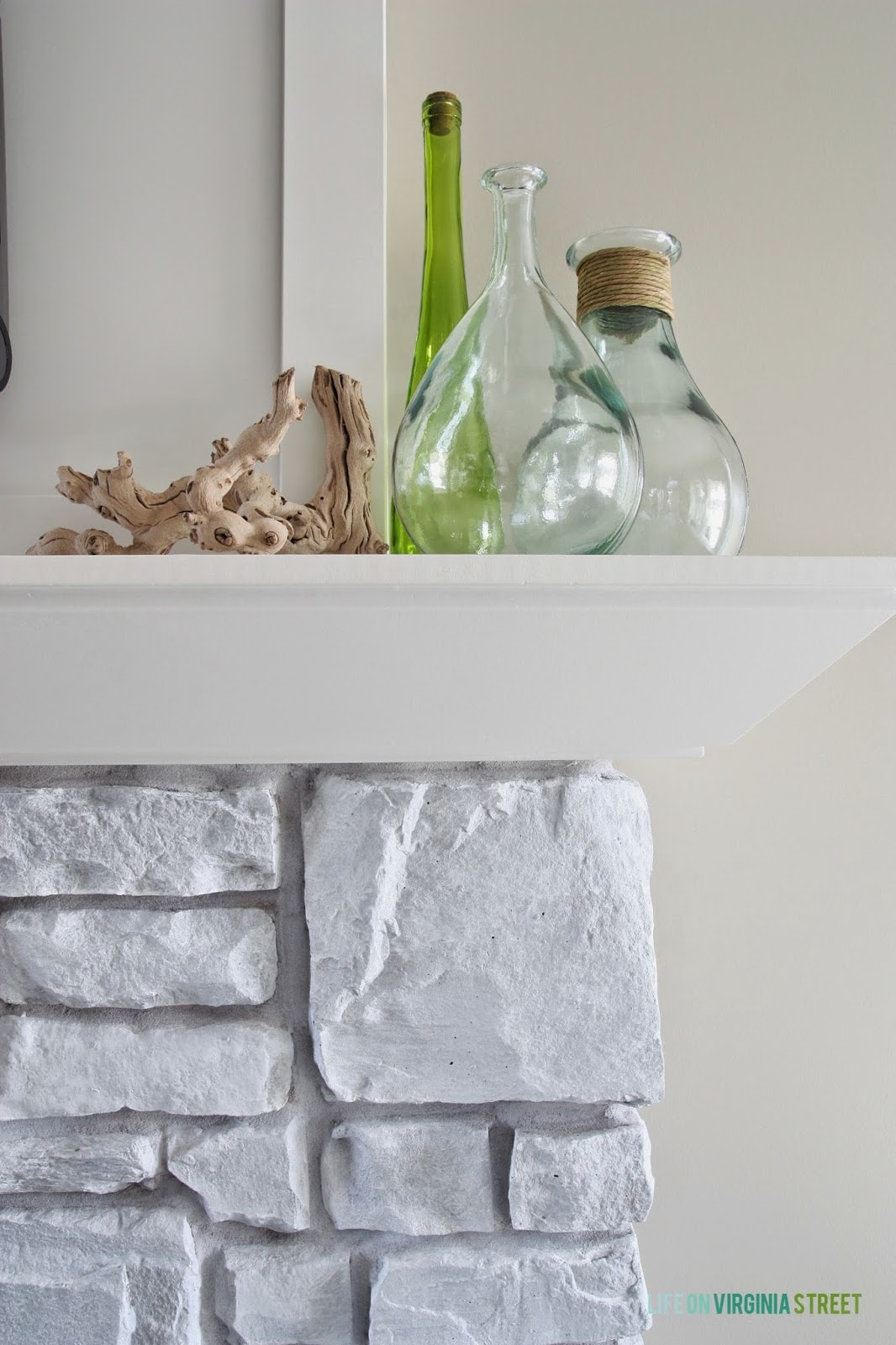 The side of the fireplace mantel with clear glass, and driftwood.