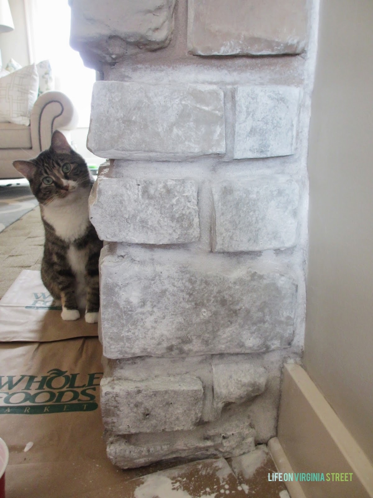 The side of the painted fireplace with a cat peeking beside it.