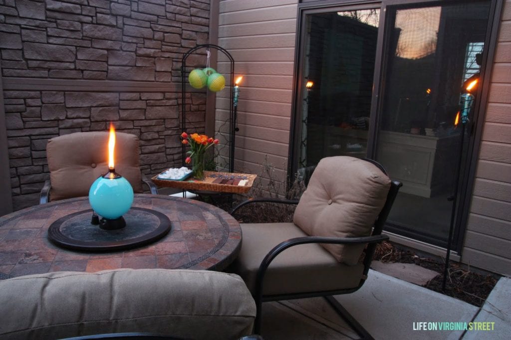 A patio table and chairs with the goody tray behind it.
