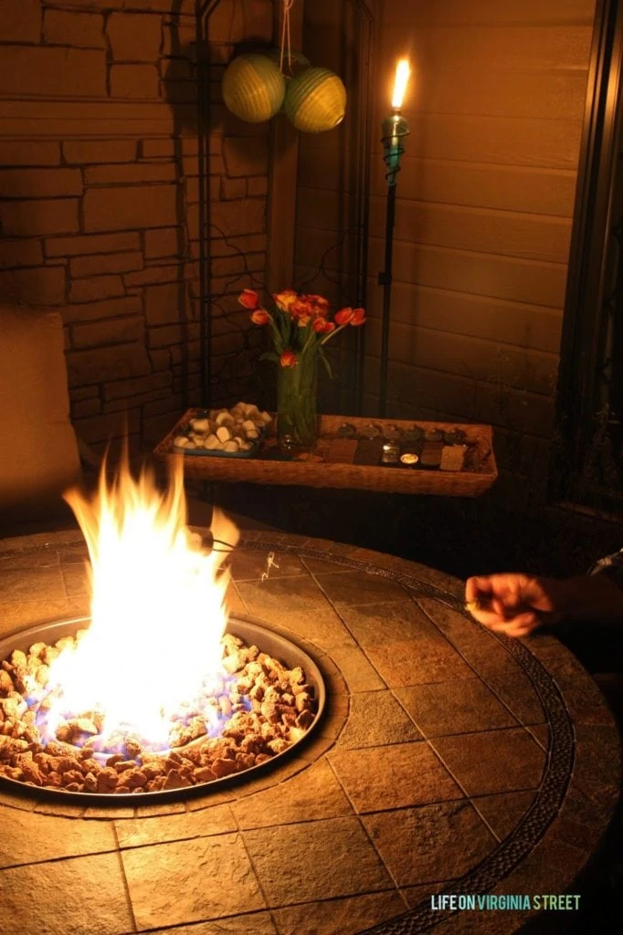 A outdoor patio fire pit that is lit and a marshmallow being heated up.
