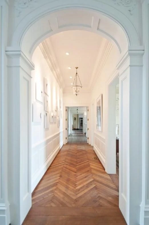 A long arched hallway with a herringbone floor.