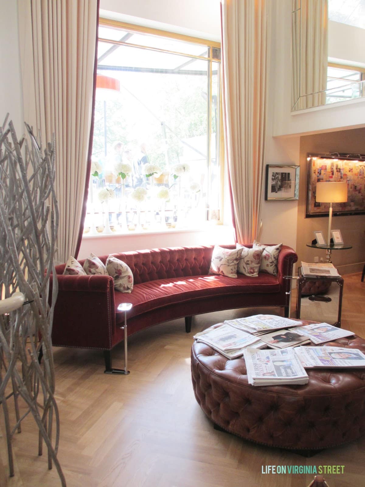 A round red couch and brown ottoman on a herringbone floor.
