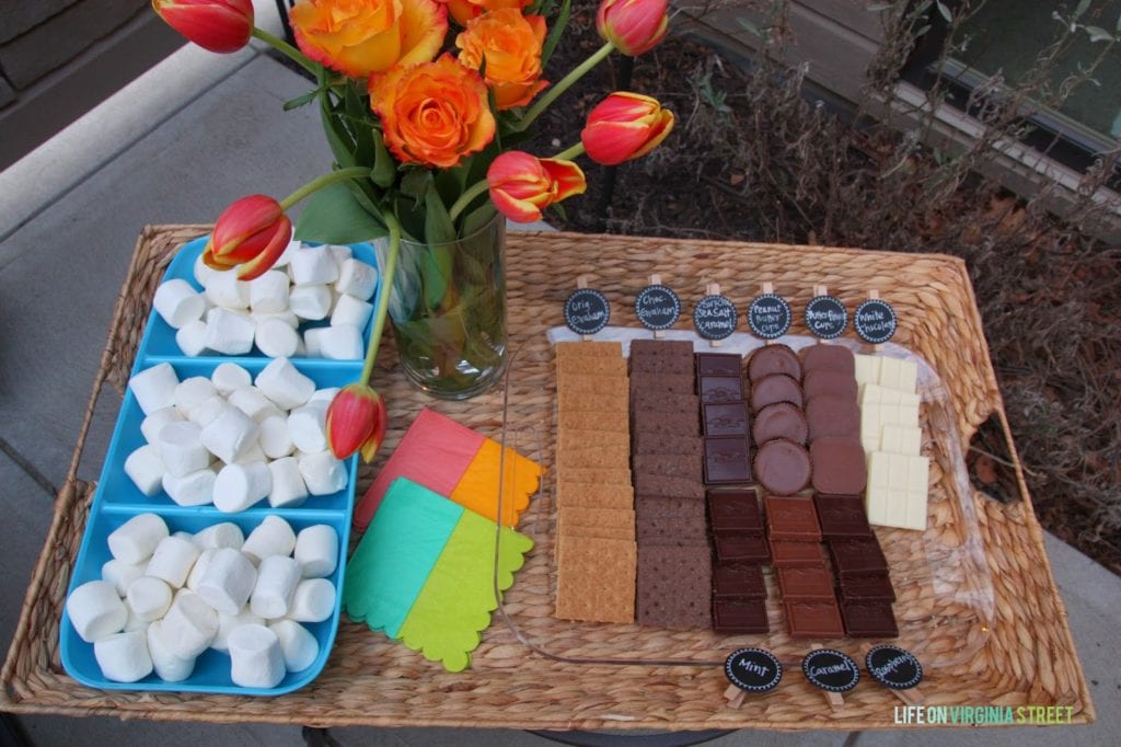 An up close look of the wicker basket with a vase filled with flowers and goodies to make s'mores.