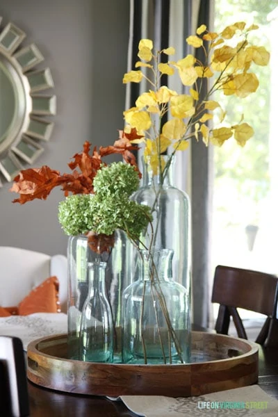 Glass vases with fall branches, leaves and flowers.