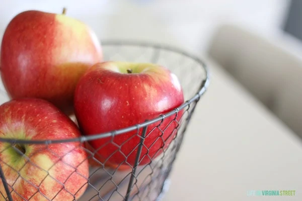 Apples in a wire basket on the counter.