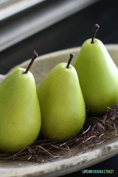 There green pears on a stone plate on the table.