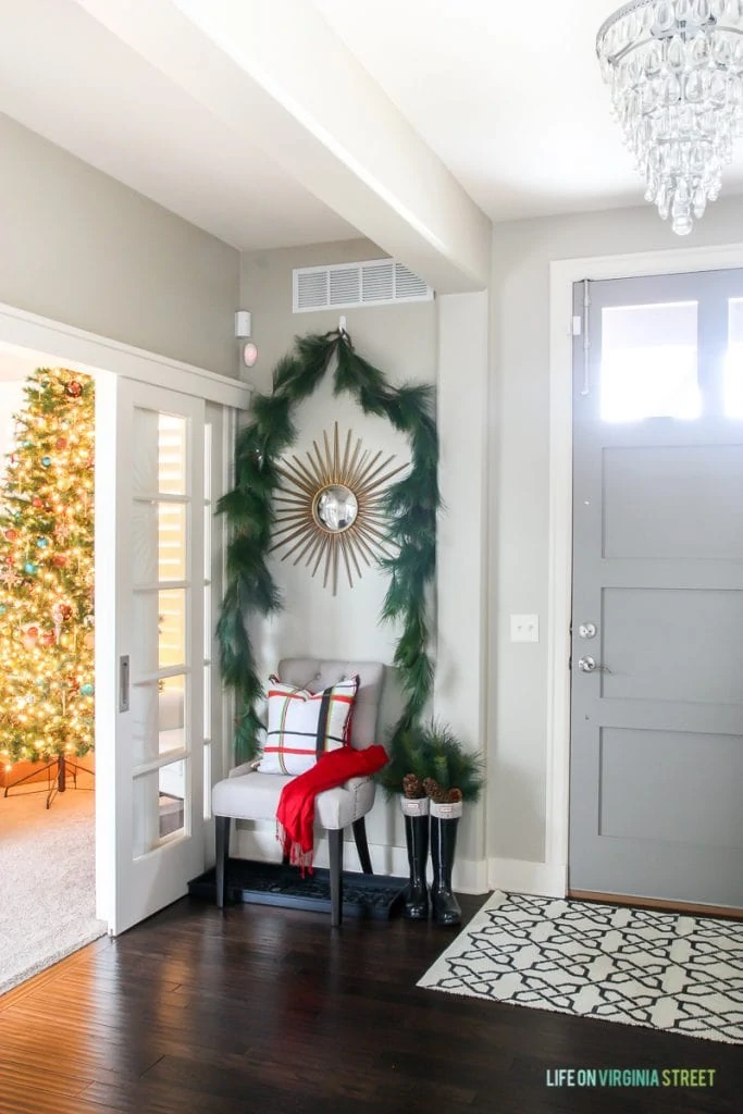 Red, white and green plaid entryway with garland swag and Hunter boots with greenery.