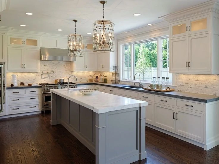 A white and gray kitchen with large chandelier lights above the island.