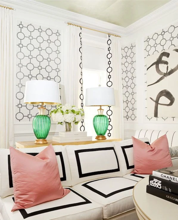Black and white walls, green lamps and pink pillows in sitting room.