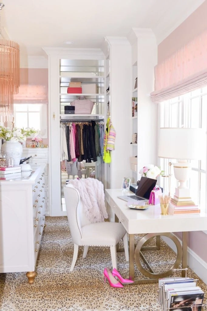 A dressing room with light pink shades, a pink throw on the chair and bright pink shoes on the floor.