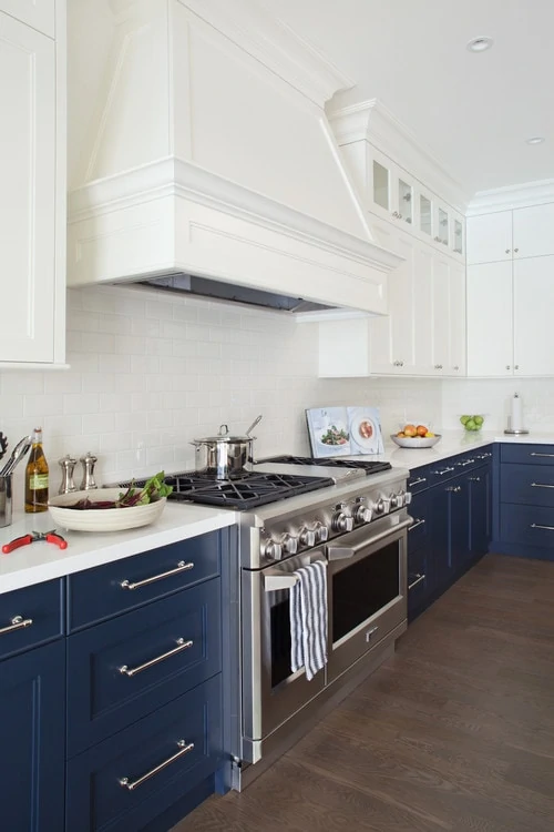 A white kitchen with blue bottom cupboards and silver handles.