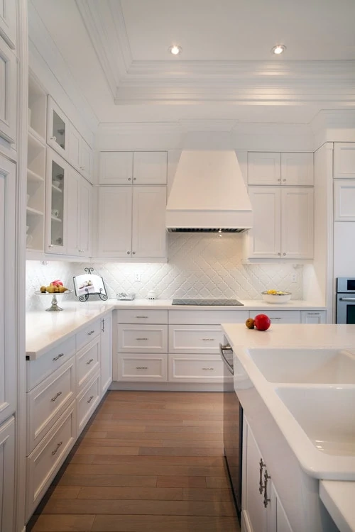 An all white kitchen with fruit on the counters.