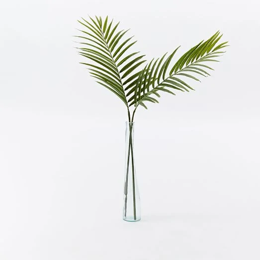 Two stems of palms in a clear glass vase.