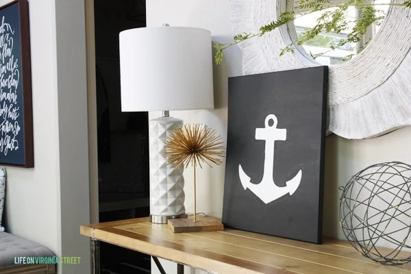 The anchor art on the table beside a wire art orb and a white lamp.