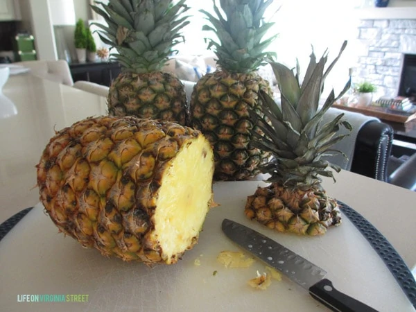 One of the pineapples with the top cut off and the knife beside it.