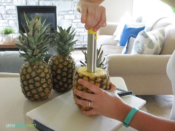 Taking a core appliance and making a hole in the middle of the pineapple.