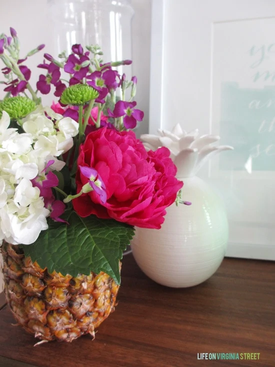 The pineapple vase on the table with a white pineapple vase beside it.