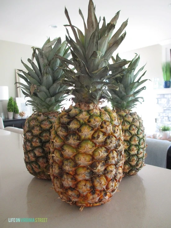 Three pineapples on the counter in the kitchen.