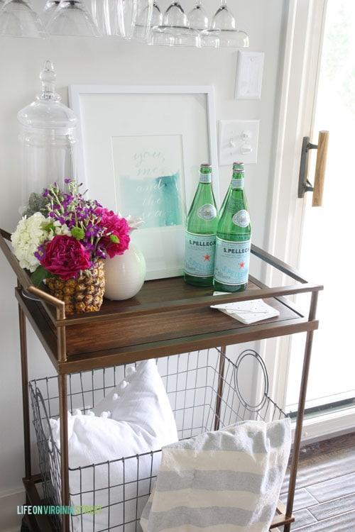 Loving this summer bar cart in this gorgeous home tour. That fresh pineapple vase with peonies and hydrangeas is on my list to make! Striped throw with pom pom pillow are also cute.