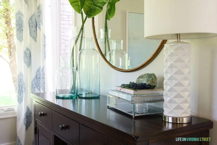 Elegant mirror over a dark wood buffet table with blue and white accents. 