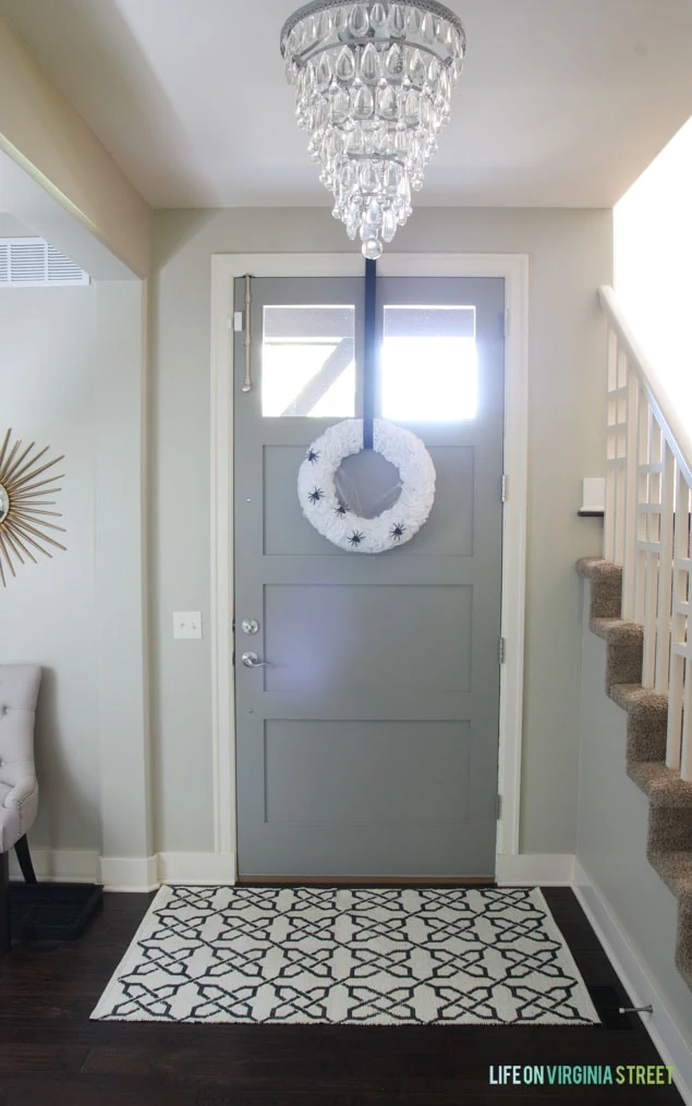 The wreath hanging on the inside of the front door and chandelier in the foyer.