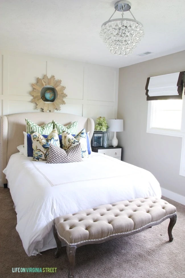 Guestroom wingback bed with white linens and green and blue accents. 