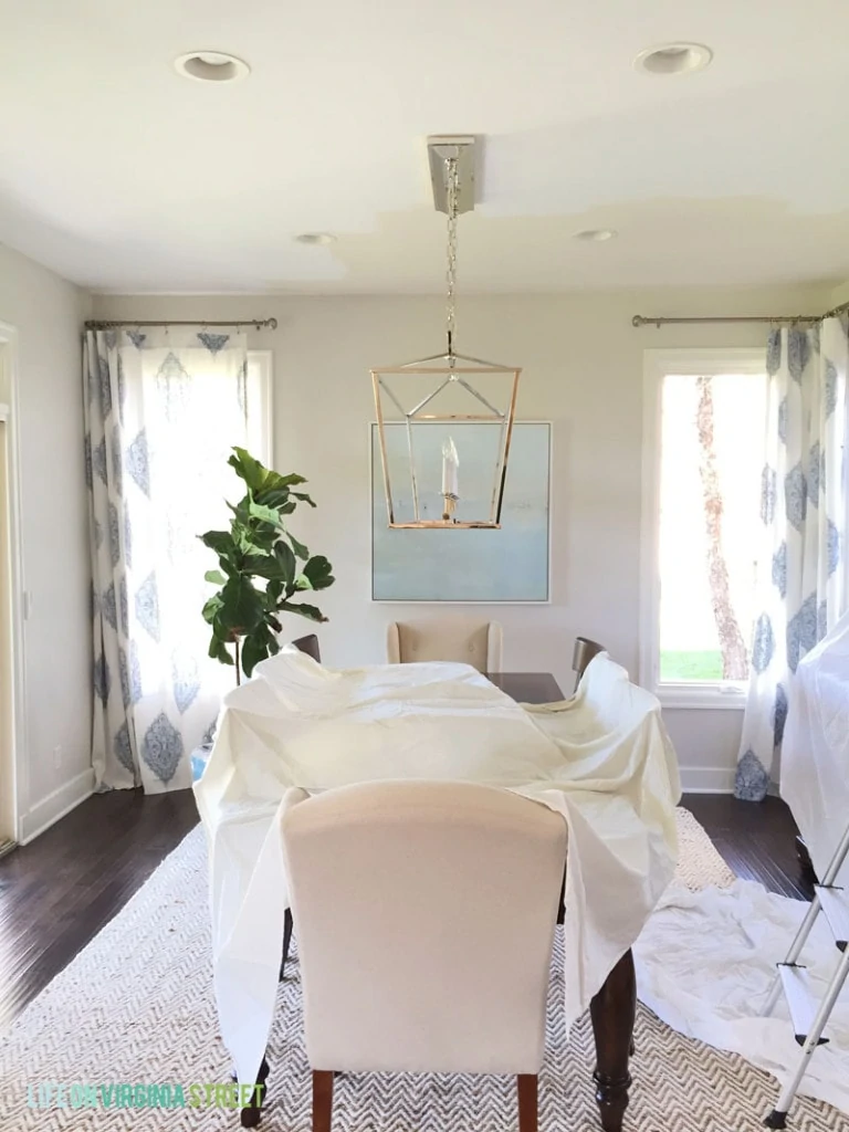 Dining room with drop sheet on table and chandelier over the table.