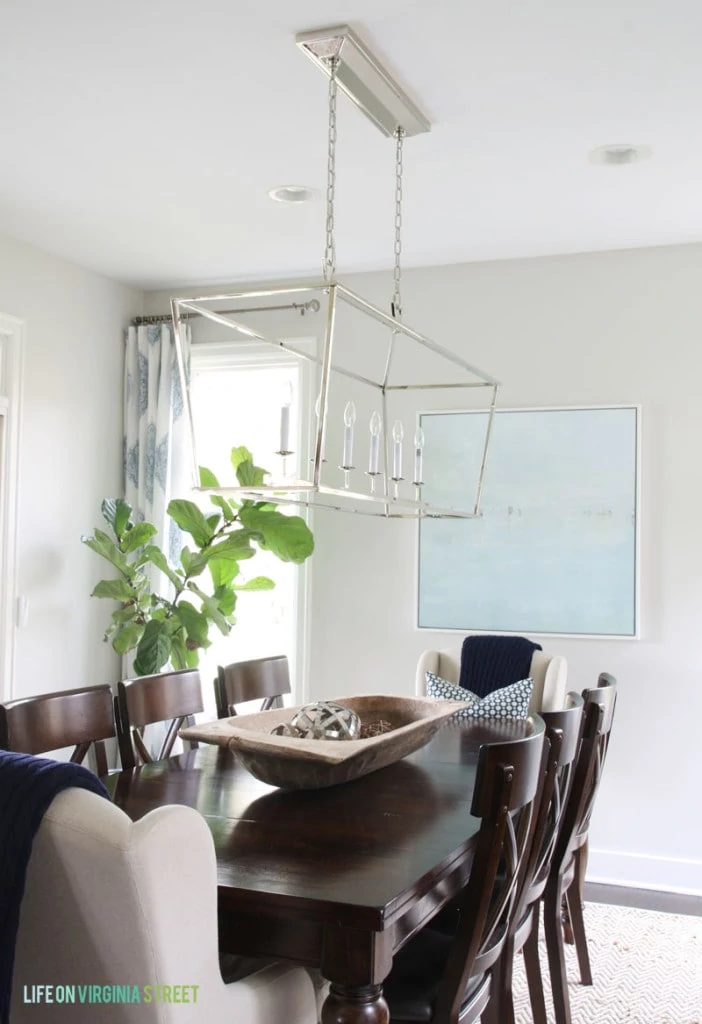 Dining room table, Darlana chandelier, and a green plant in corner of room.