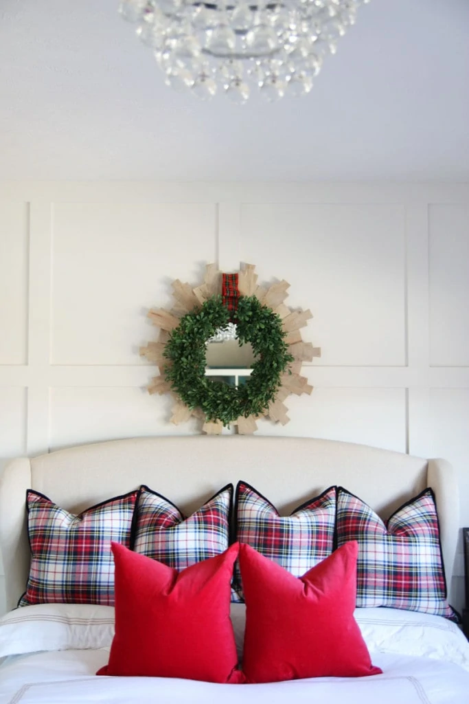 Christmas Guest Room with green wreath on wall and chandelier above the bed.