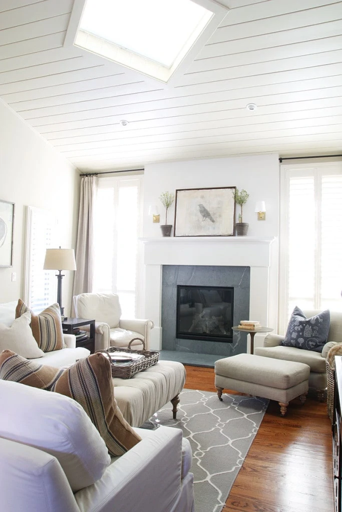 Living Room. Love the look of this dark grey slate fireplace mixed with the neutral warm fabric patterns and creme colored walls. The artwork above the fireplace is simple, matched with minimal green shrubbery and candle sconces. - Neutral Home Tour - Life On Virginia Street