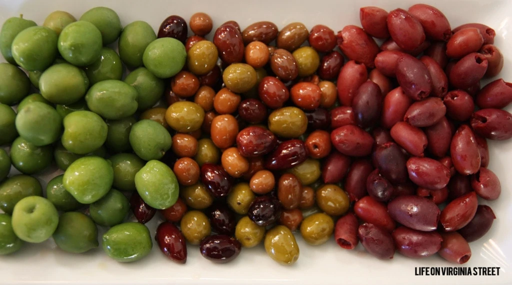 Mezzetta Olives in green, and red on a white plate.
