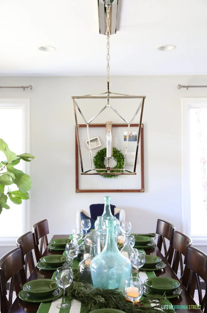 A Christmas dining room with green and white striped tablecloth and large recycled glass bottles.