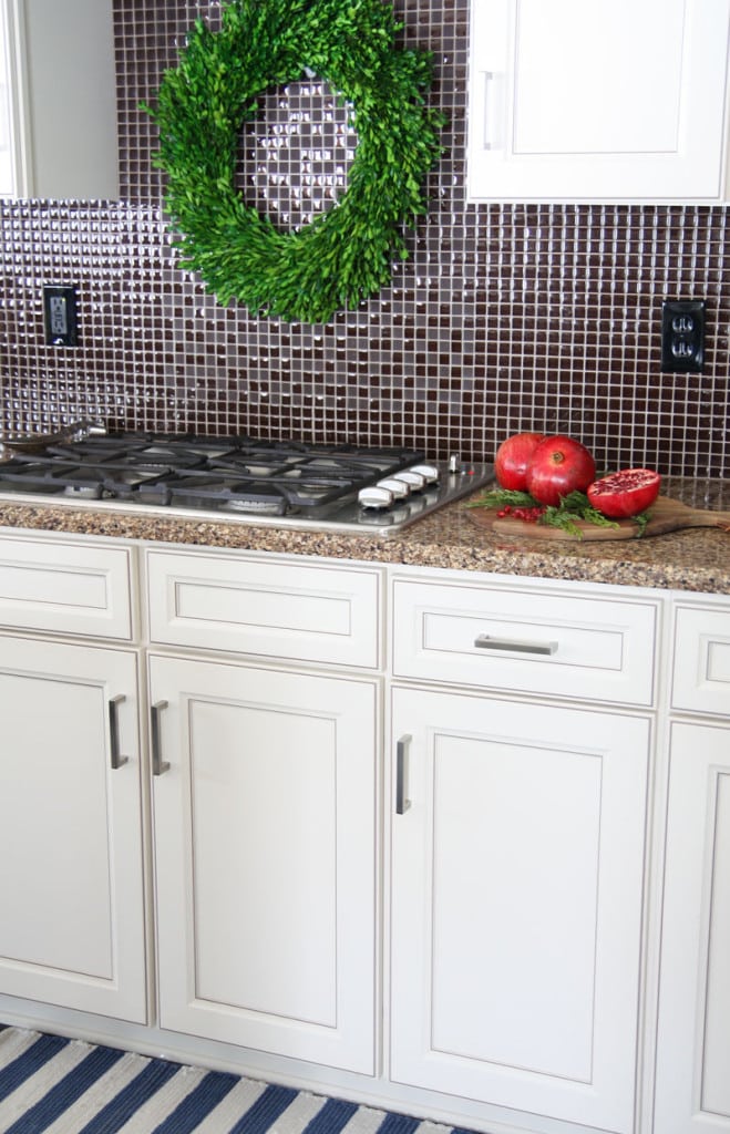 A Christmas kitchen range with pomegranates and a boxwood wreath above the stove.