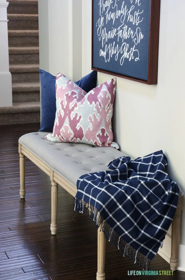 Fall Entryway with bench beside the wall and pink and blue pillows on it.