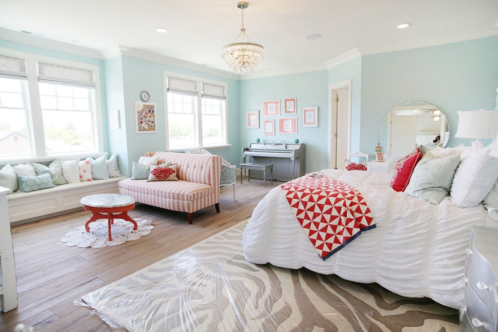 Light blue walls, white bedding. Red blankets on bed.