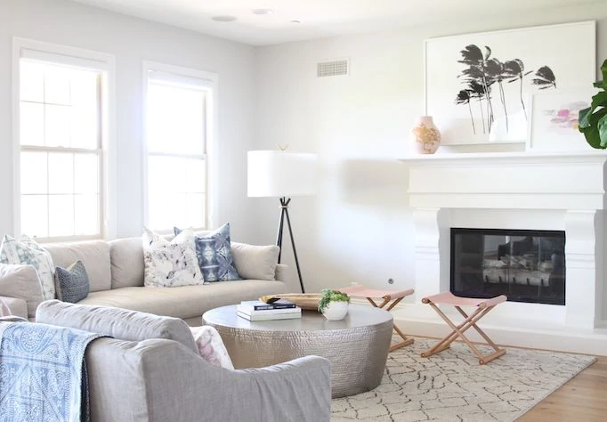 Neutral living room with round coffee table, and soft pink touches.
