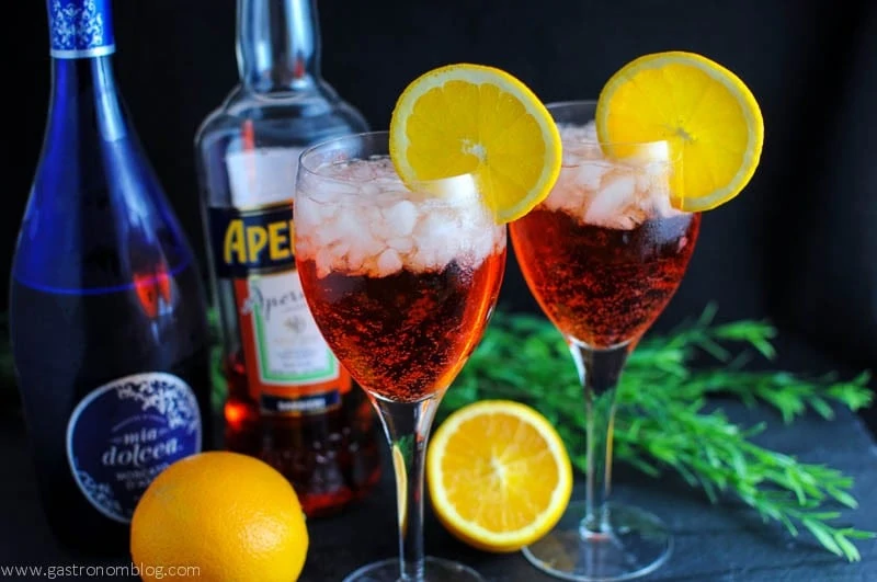 Aperol Spritz in wine glasses with ice cubes and orange slices on the rim.