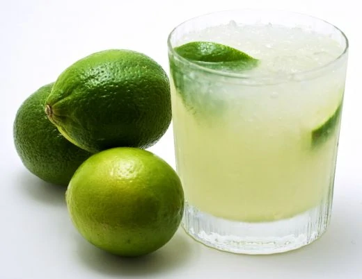 Caipirinha with 3 limes beside the glass.