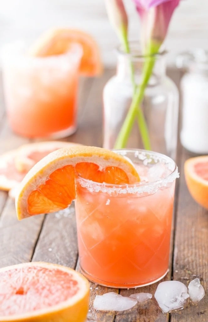 Grapefruit Salty Dog in a glass with an orange slice in the rim on a table.