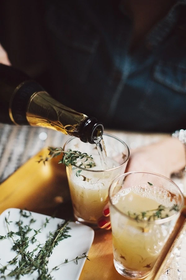 Pear Nectar Thyme Mimosas with champagne being poured into the glasses.