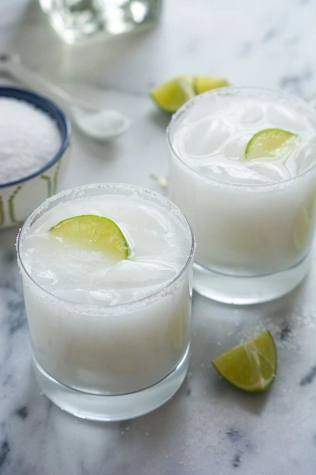 Skinny Coconut Margarita with lime inside them on the marble table.