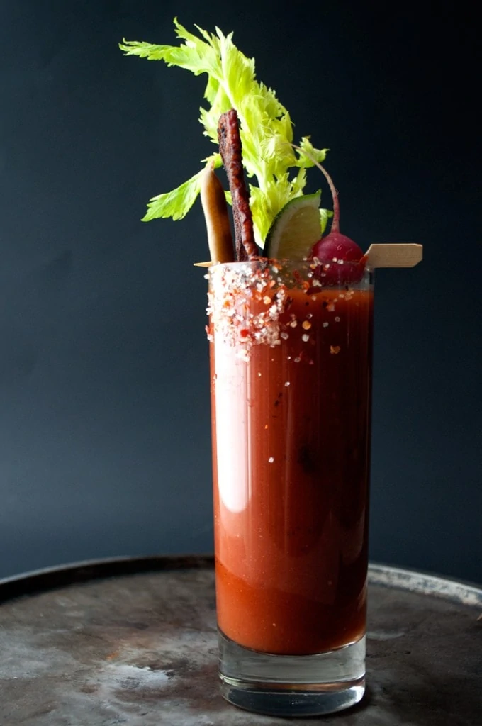 Spicy Bloody Mary with Candied Bacon in a tall glass with celery.