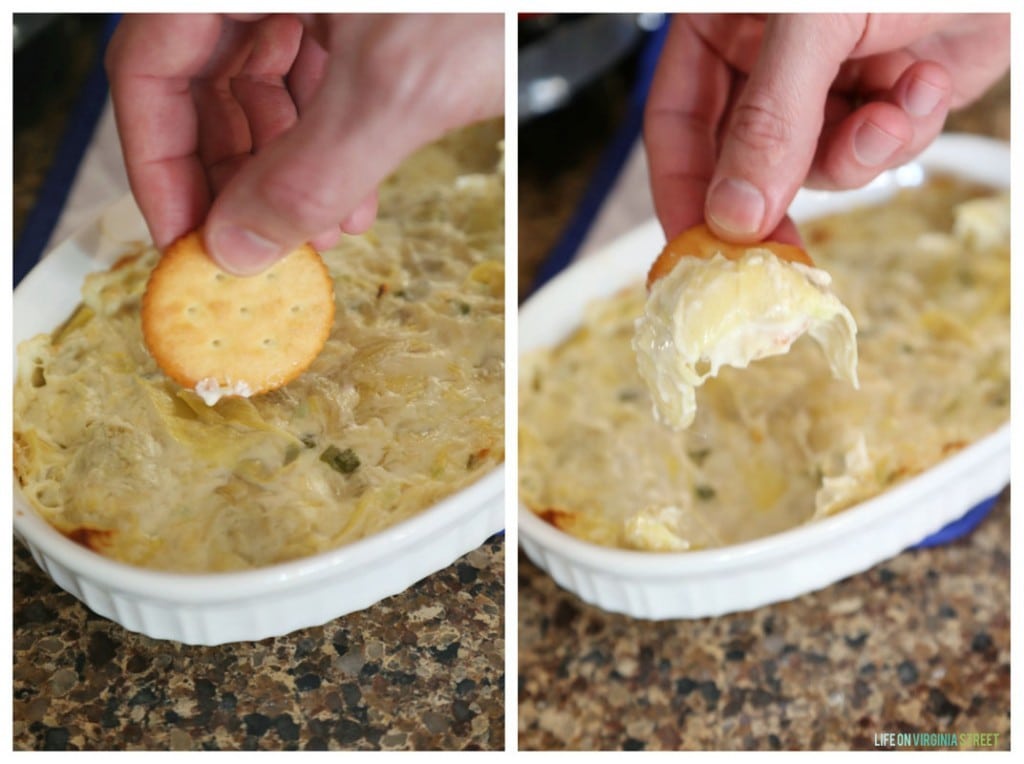 Someone dipping the cracker into the artichoke dip.