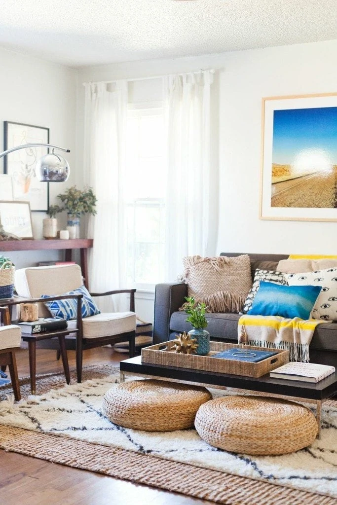 A bonus room with a small coffee table, a small gray couch, armchairs in the corner and a silver lamp.