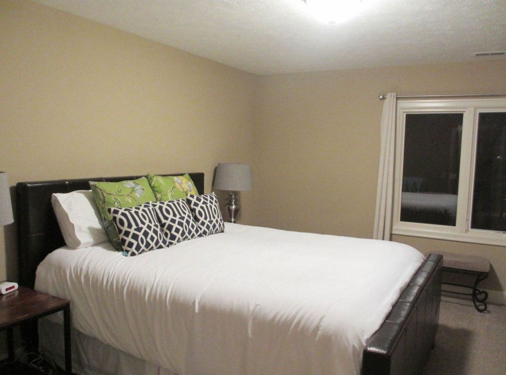 Guest-Bedroom with a a bed by the cream coloured wall and pillows on the bed.