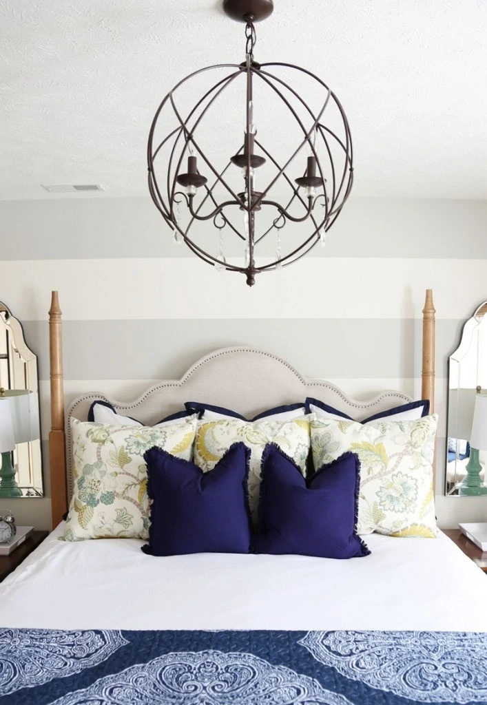 A wrought iron large chandelier over top of the bed.
