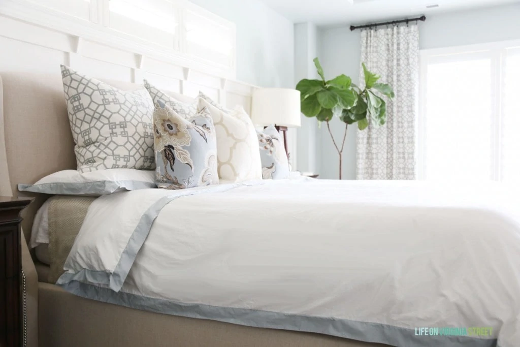 A white duvet with light blue trim on the bed.