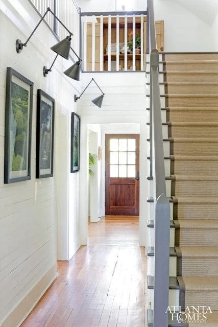 A narrow hallway with steep stairs and swing arm lights in the hallway.